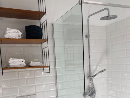 helles Bad mit Ablage für Handtücher und mehr moderne Dusche mit Glastrennwand und Regenwasserbrause